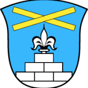 Das Wappen der Gemeinde Staudach-Egerndach. Blauer Hintergrund, mit einem gemauerten weißen Stufengiebel. An der Spitze des Gibels befindet sich eine heraldische Lilie. Oberhalb davon ein gelbes Kreuz.